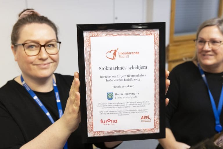 Bildet viser en dame som holder fram en diplom bedriften hennes har fått.